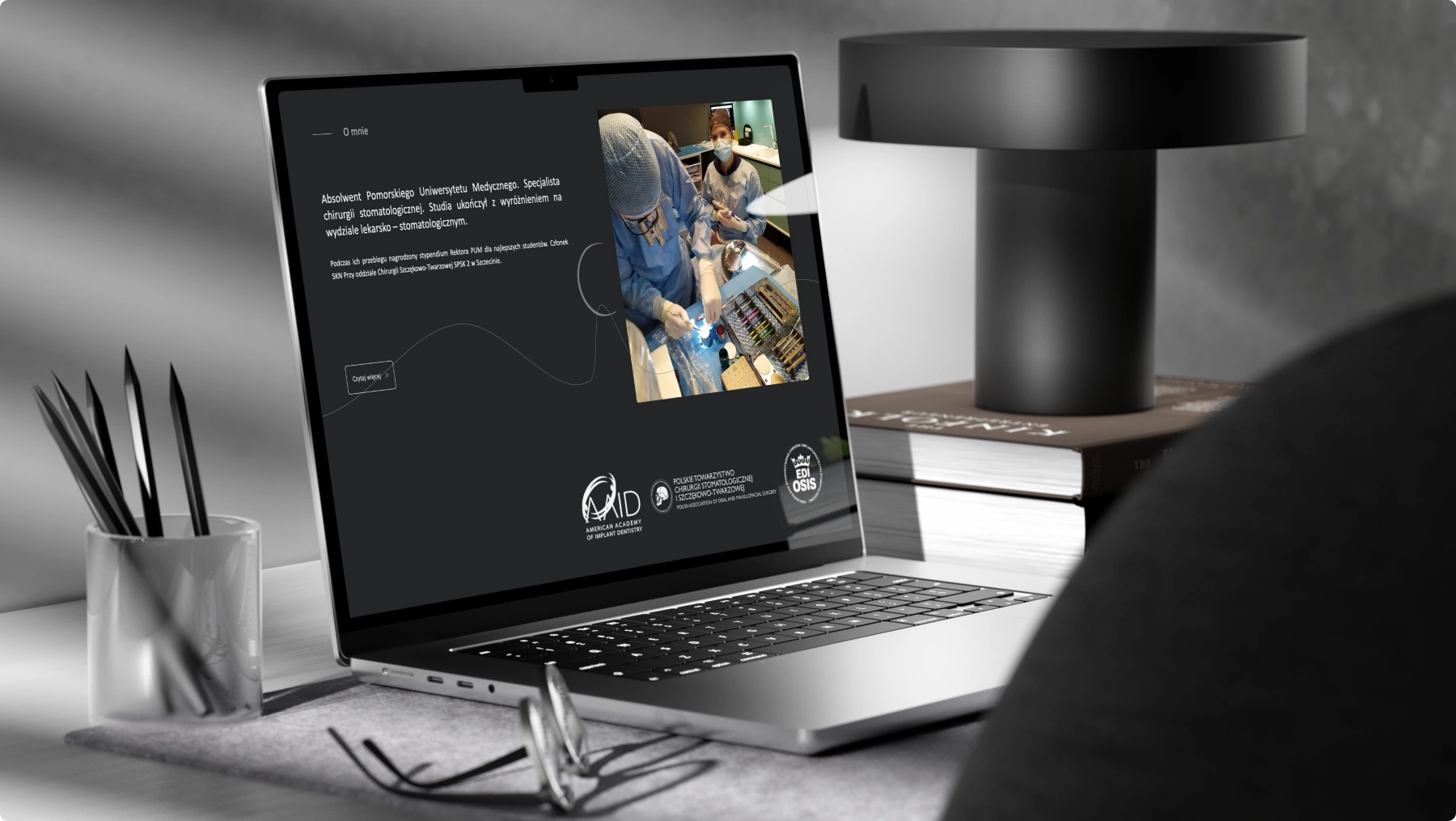 Zdjęcie laptopa wyświetlającego stronę chirurga stomatologicznego. Widoczna biografia, osiągnięcia oraz zdjęcie zespołu chirurgicznego podczas zabiegu.